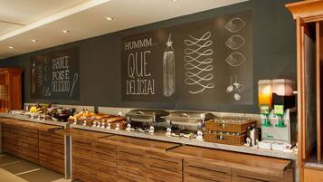 A buffet area with a chalkboard wall displaying food-related text and drawings, a buffet counter with various food items, and a juice dispenser.