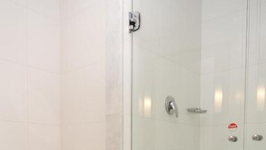 Een badkamer met een toilet, een douche met glazen wanden en een betegelde vloer.
