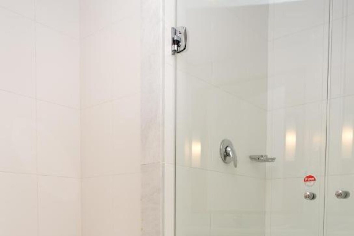 Een badkamer met een toilet, een douche met glazen wanden en een betegelde vloer.