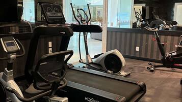 Un gimnasio con cintas de correr, elípticas y un espejo grande.
