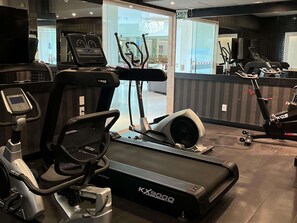Ein Fitnessstudio mit Laufbändern, Crosstrainern und einer Spiegelwand.