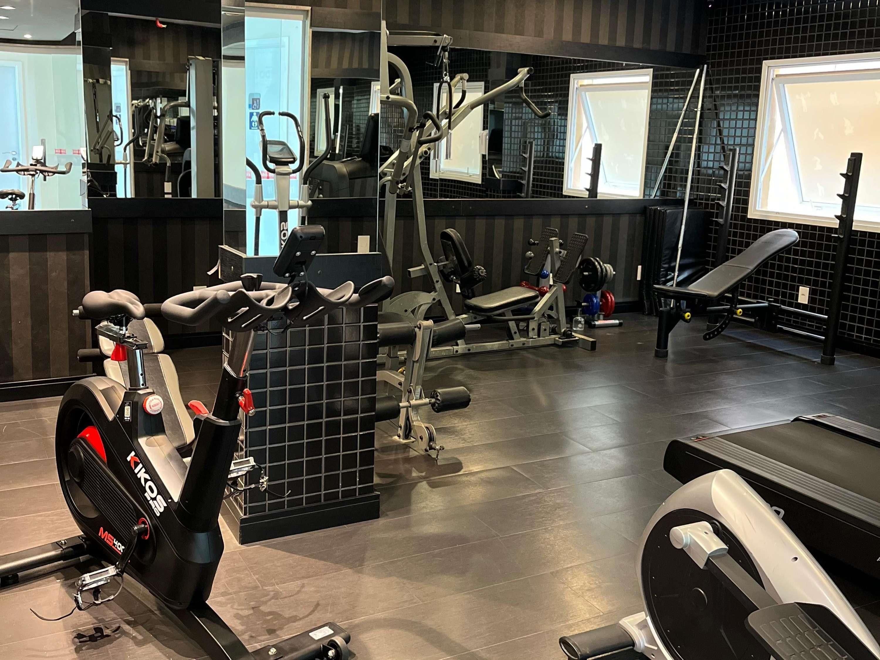 A gym with various exercise equipment including treadmills, weight machines, and a rowing machine.