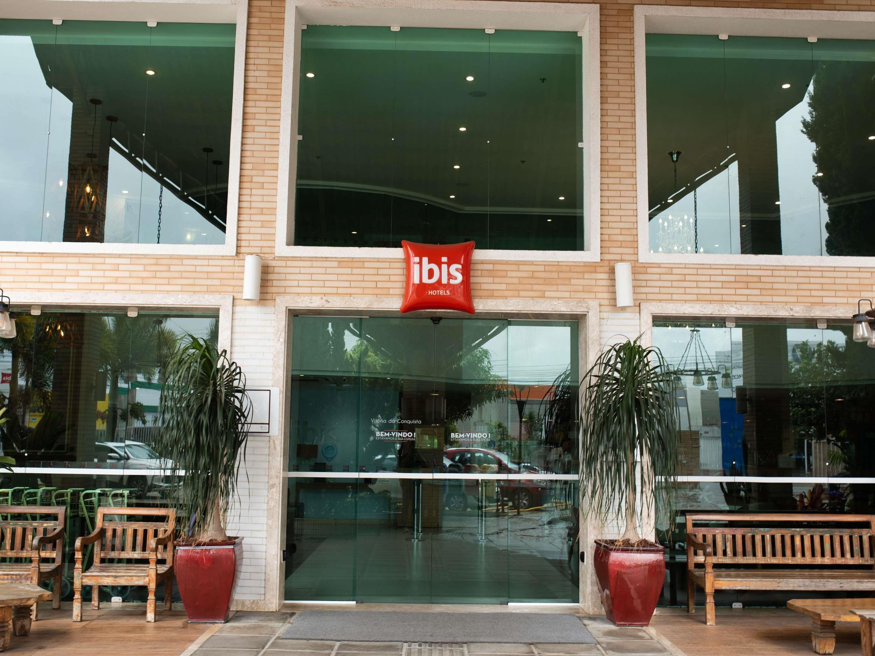 Das ibis Hotel im modernen Design mit großen Fenstern, Pflanzkübeln und Holzbanken.