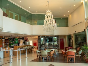 Een hotellobby met een bar, zithoek en een kroonluchter.