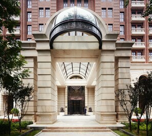 A grand entrance with a large archway, a glass ceiling, and a statue in front.