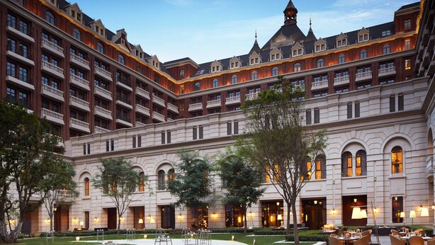 A large hotel with multiple balconies, a courtyard with outdoor seating, and a well-lit facade. - The Ritz-Carlton, Tianjin (Tianjin)