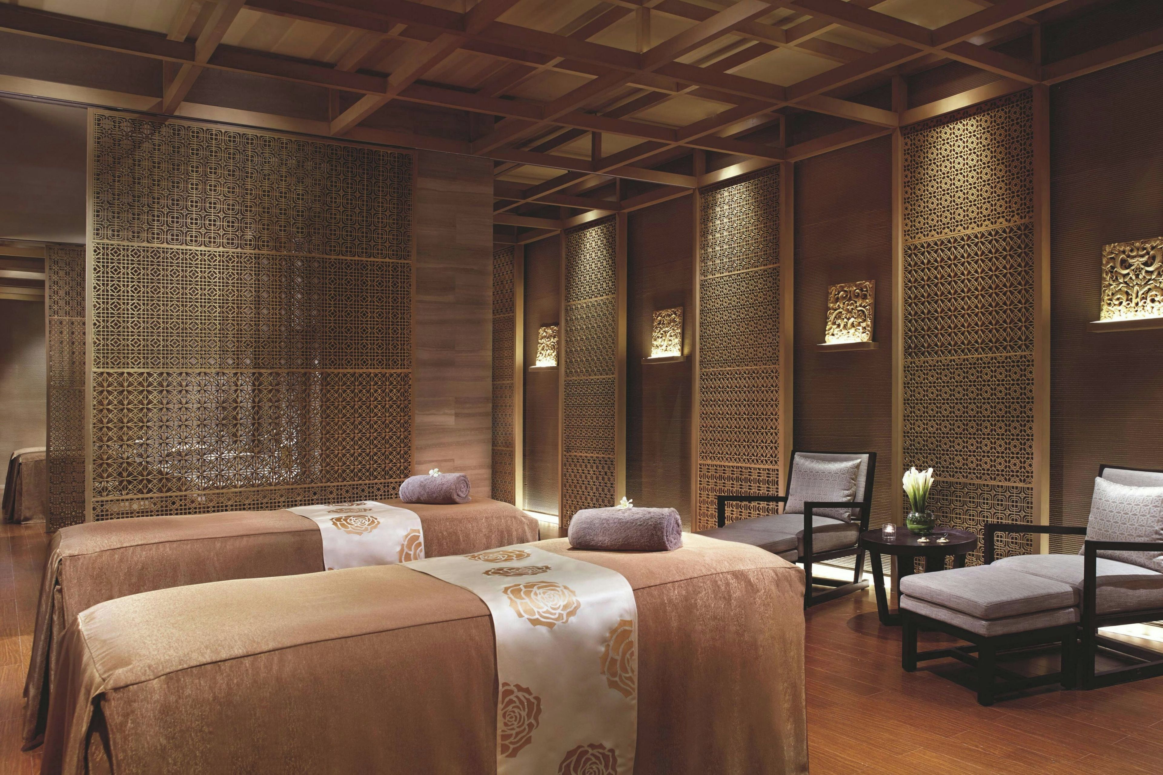A traditional-style room with two beds, a chair, and a small table.