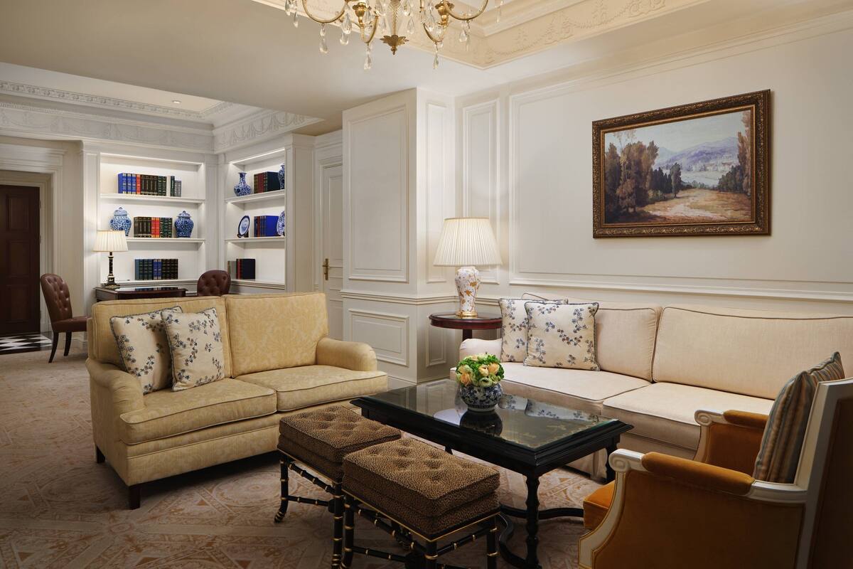 A classic living room with a beige sofa, a coffee table, and a bookshelf filled with books and decorative items.