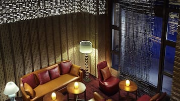 A modern lounge with a patterned wall, leather seating, and ambient lighting.