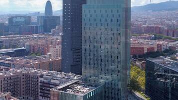 Un edificio de gran altura con fachada de vidrio moderno, rodeado de otros edificios y una gasolinera en primer plano.