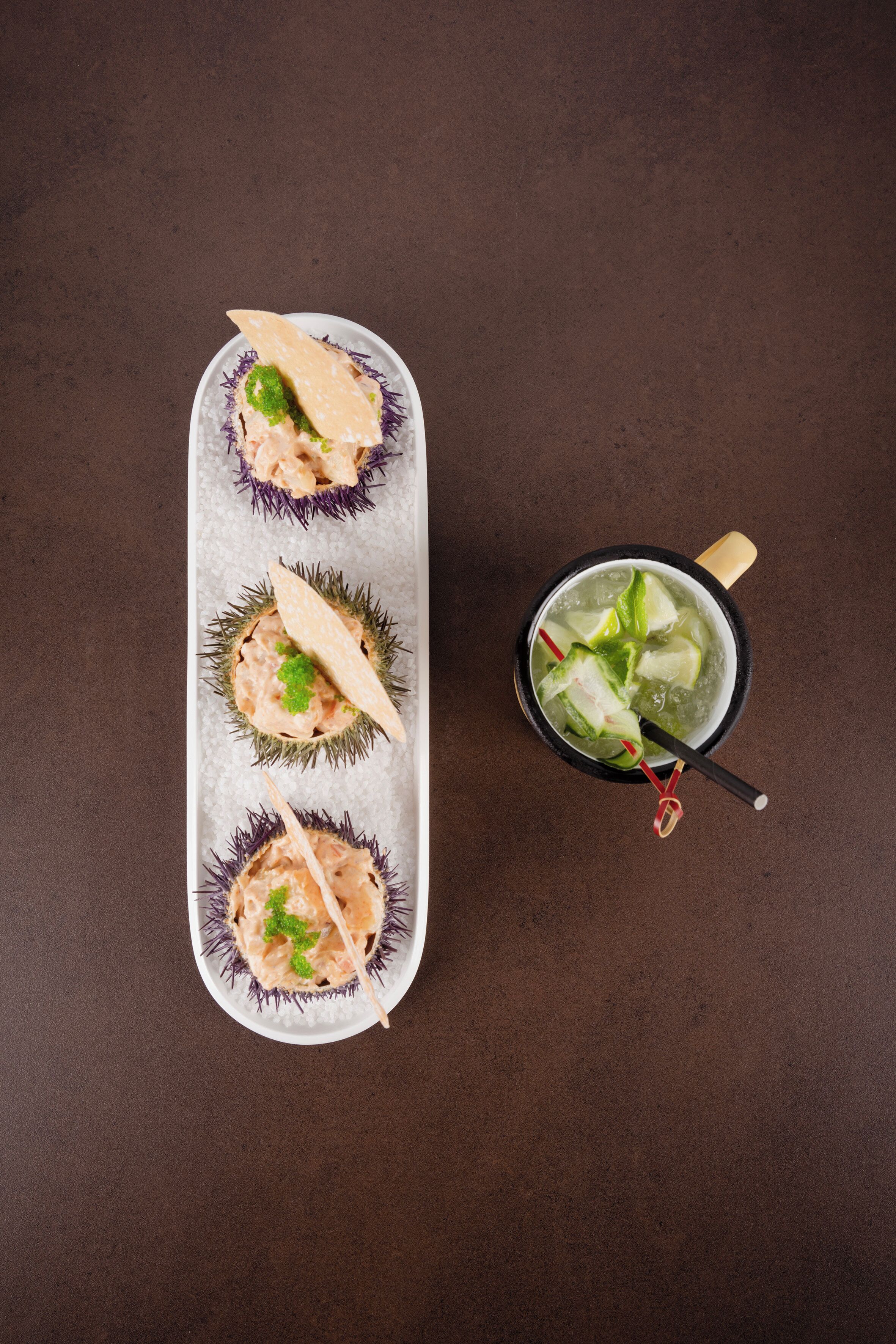 Una bandeja de sushi con tres piezas y una taza de té.