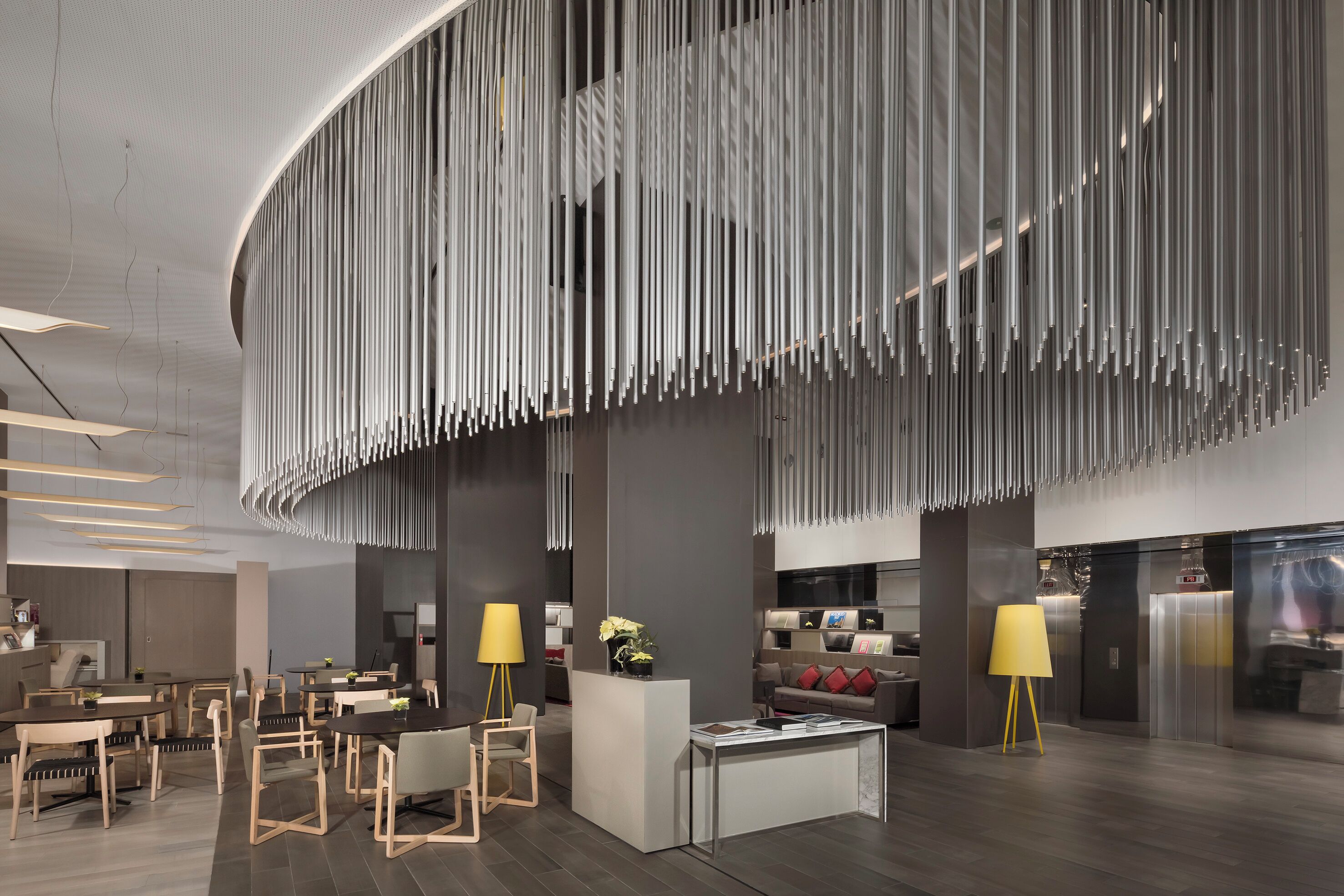Un moderno vestíbulo de hotel con un mostrador de recepción central, zona de estar y un diseño de techo único.