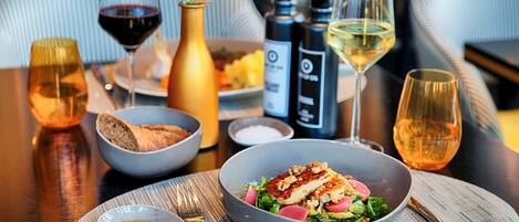 A dining table with a meal, wine glasses, and condiments.
