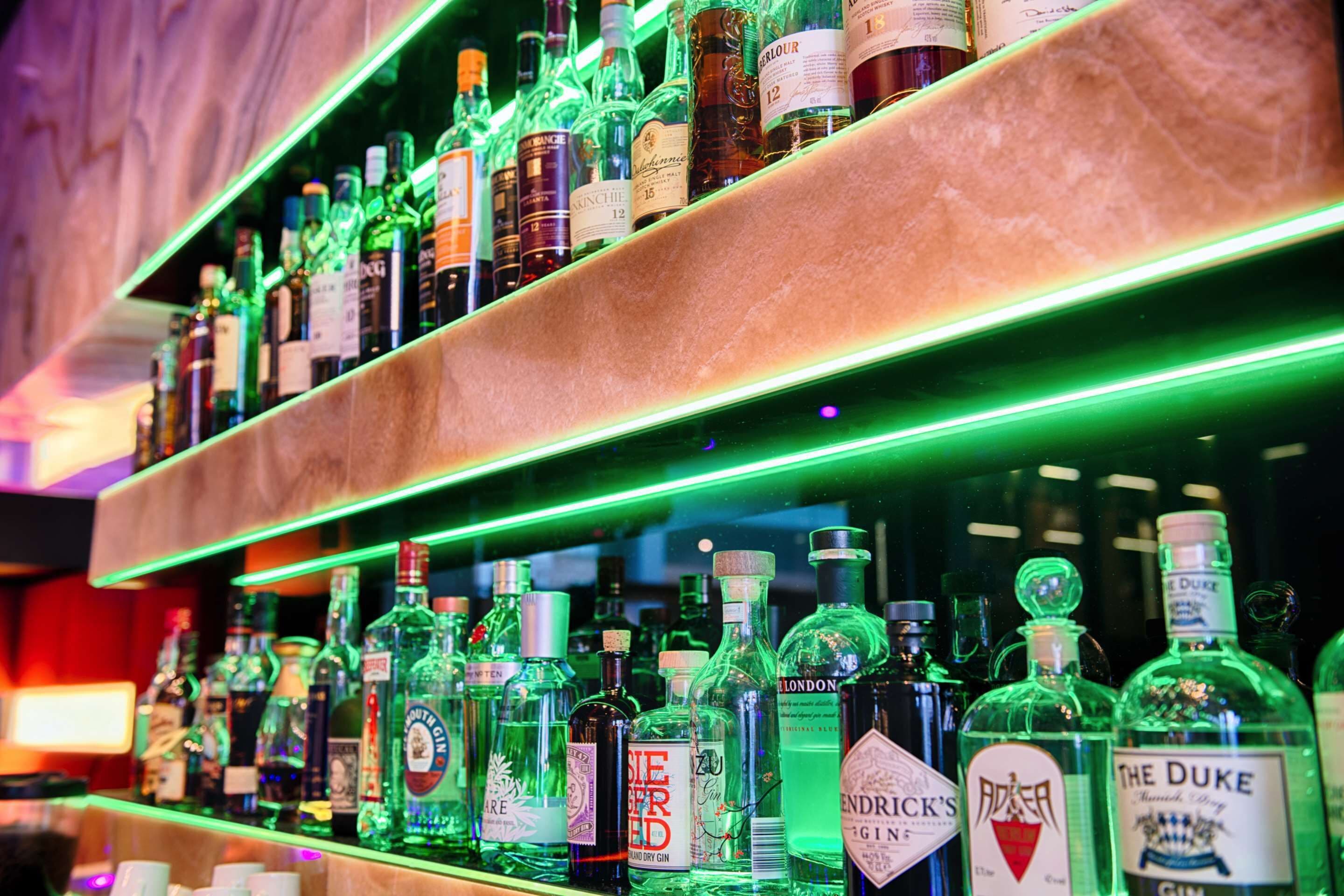 Un bar avec de nombreuses étagères remplies de bouteilles d’alcool.