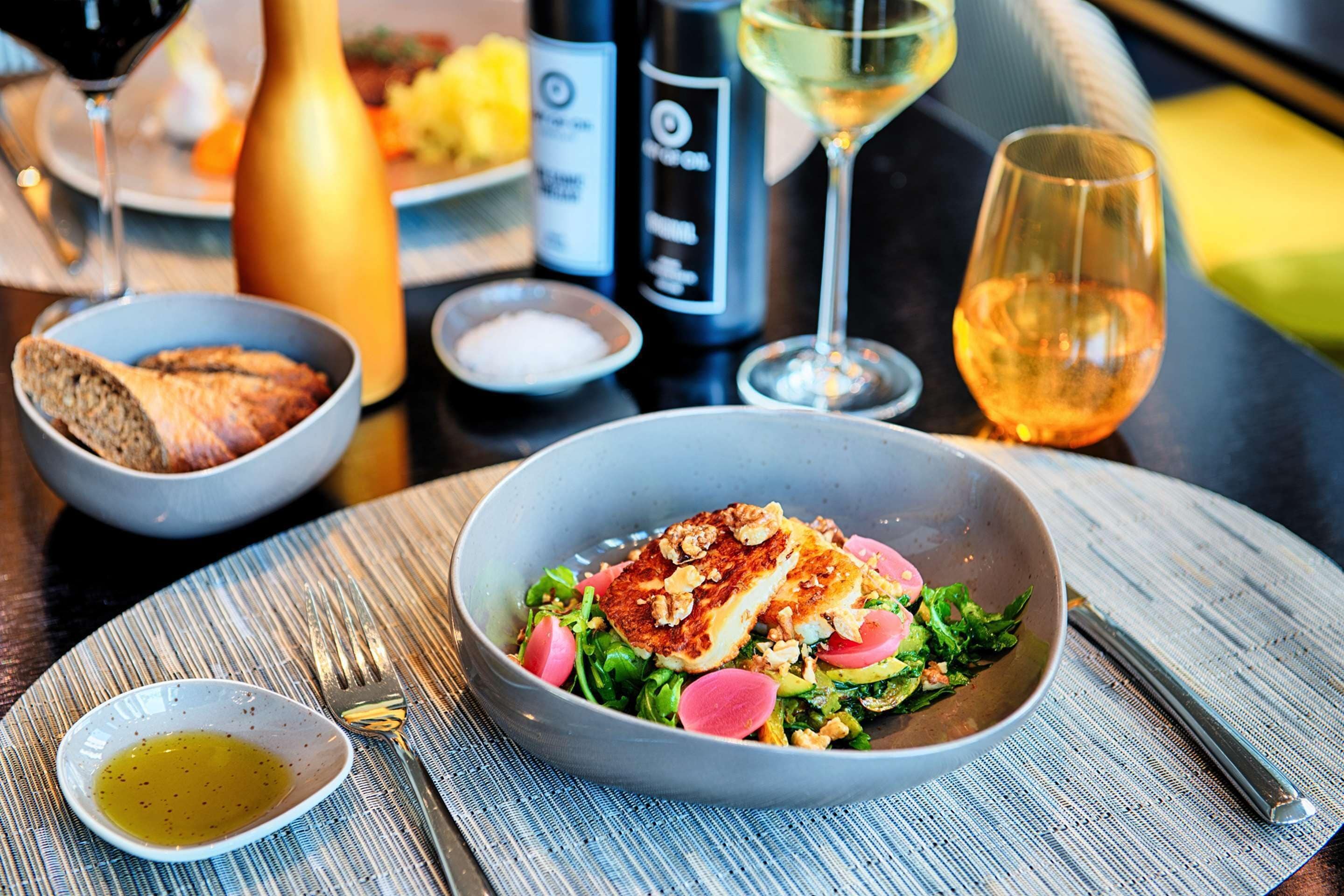 A dining table with a meal, wine glasses, and a bottle.