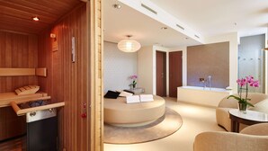 A modern spa room with a wooden sauna, a round seating area with a small table, and a large mirror. - Steigenberger Hotel Am Kanzleramt (Berlin)