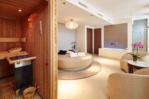 Ein moderner Wellnessraum mit einer Holzzimmer, einer runden Sitzecke mit kleinem Tisch und einem großen Spiegel.