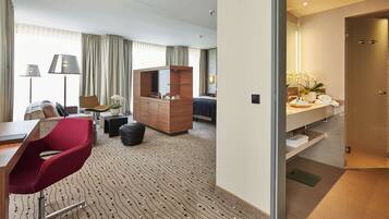 Habitación de hotel con escritorio, silla roja, cómoda de madera y un espejo grande.