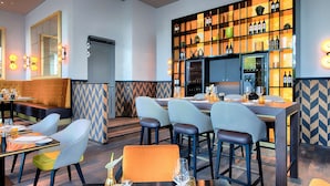 A restaurant with a bar area, seating arrangements, and a wine display. - Steigenberger Hotel Am Kanzleramt (Berlin)