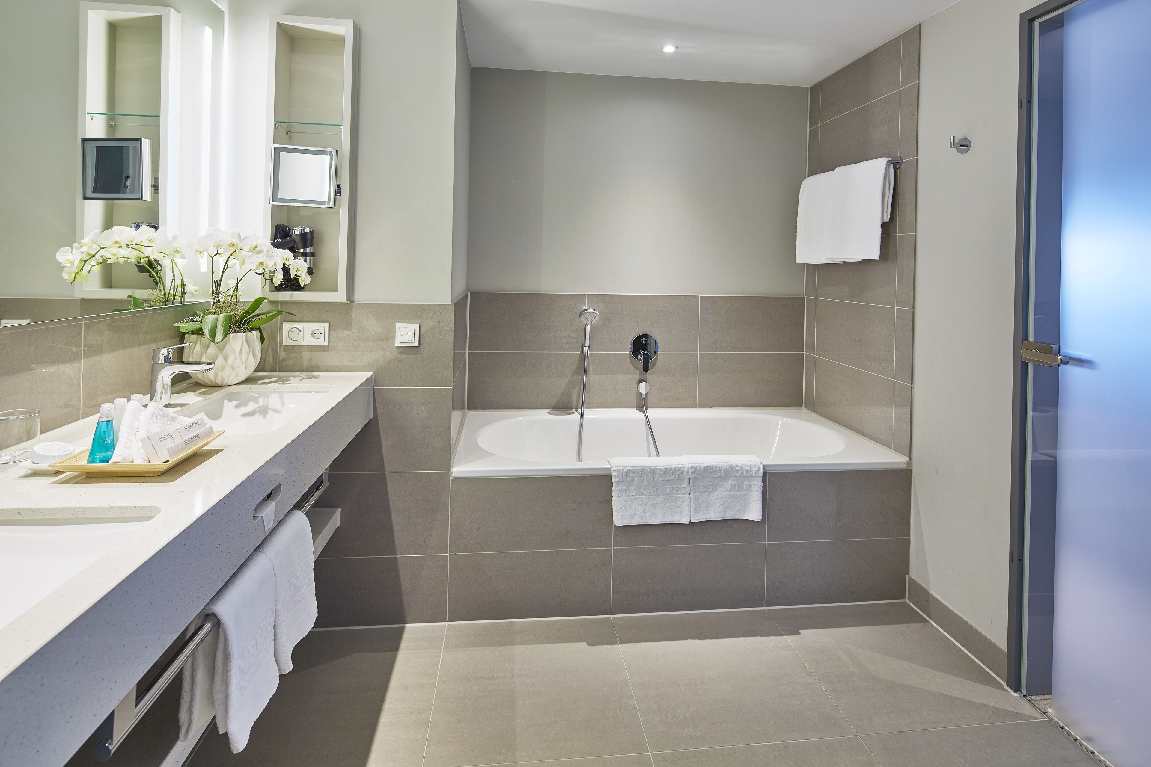 A modern bathroom with a bathtub, a vanity with a mirror, and a sink.