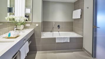 A modern bathroom with a bathtub, a vanity with a mirror, and a sink.