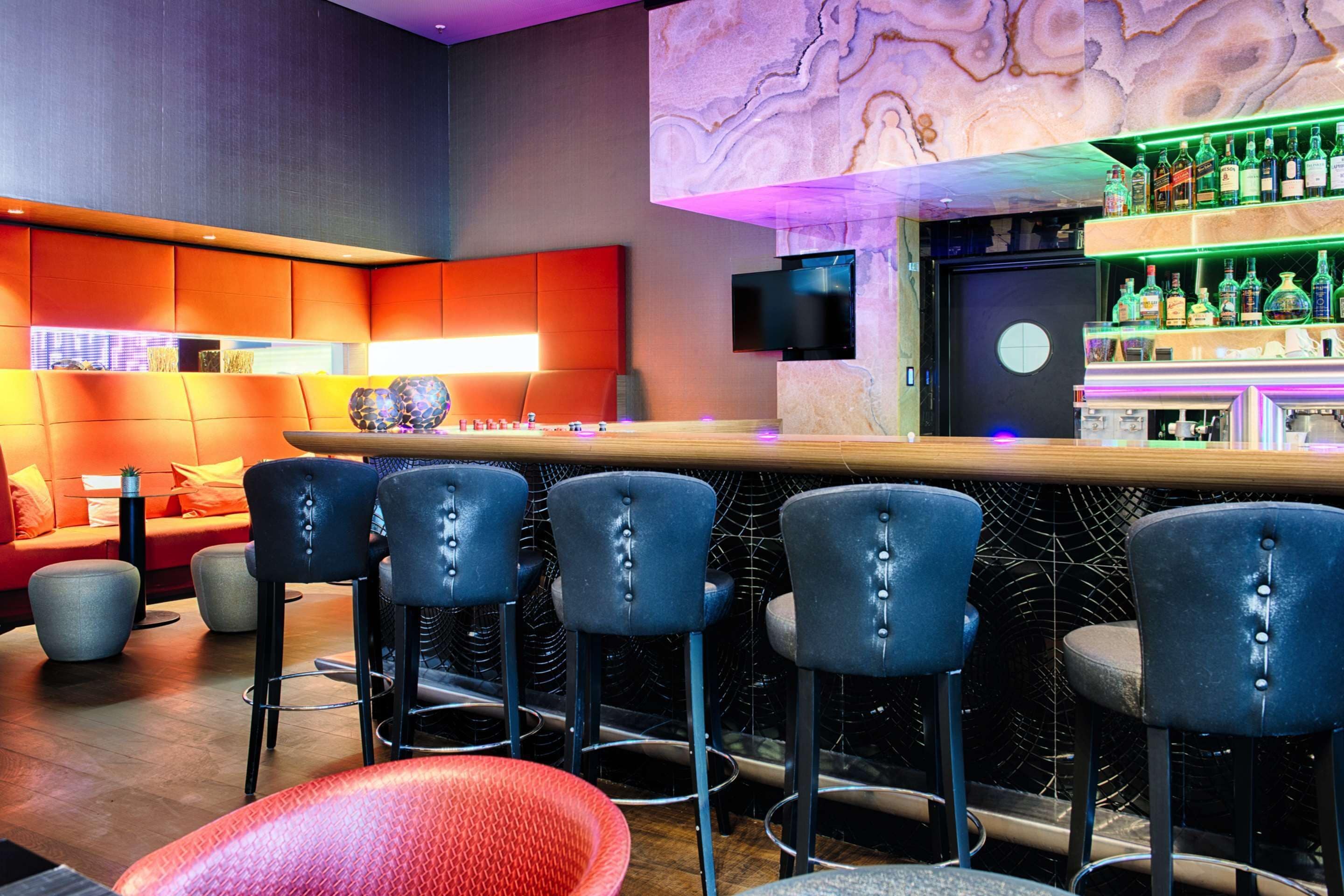 A bar area with multiple stools, a counter, and a television screen.