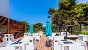 A deck with white tables and chairs, and turquoise umbrellas. - Hotel Souani (Ait Youssef Ou Ali)