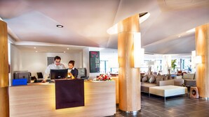 A modern reception area with a reception desk, a digital display, and a seating area with a sofa and chairs. - Hotel Souani (Ait Youssef Ou Ali)