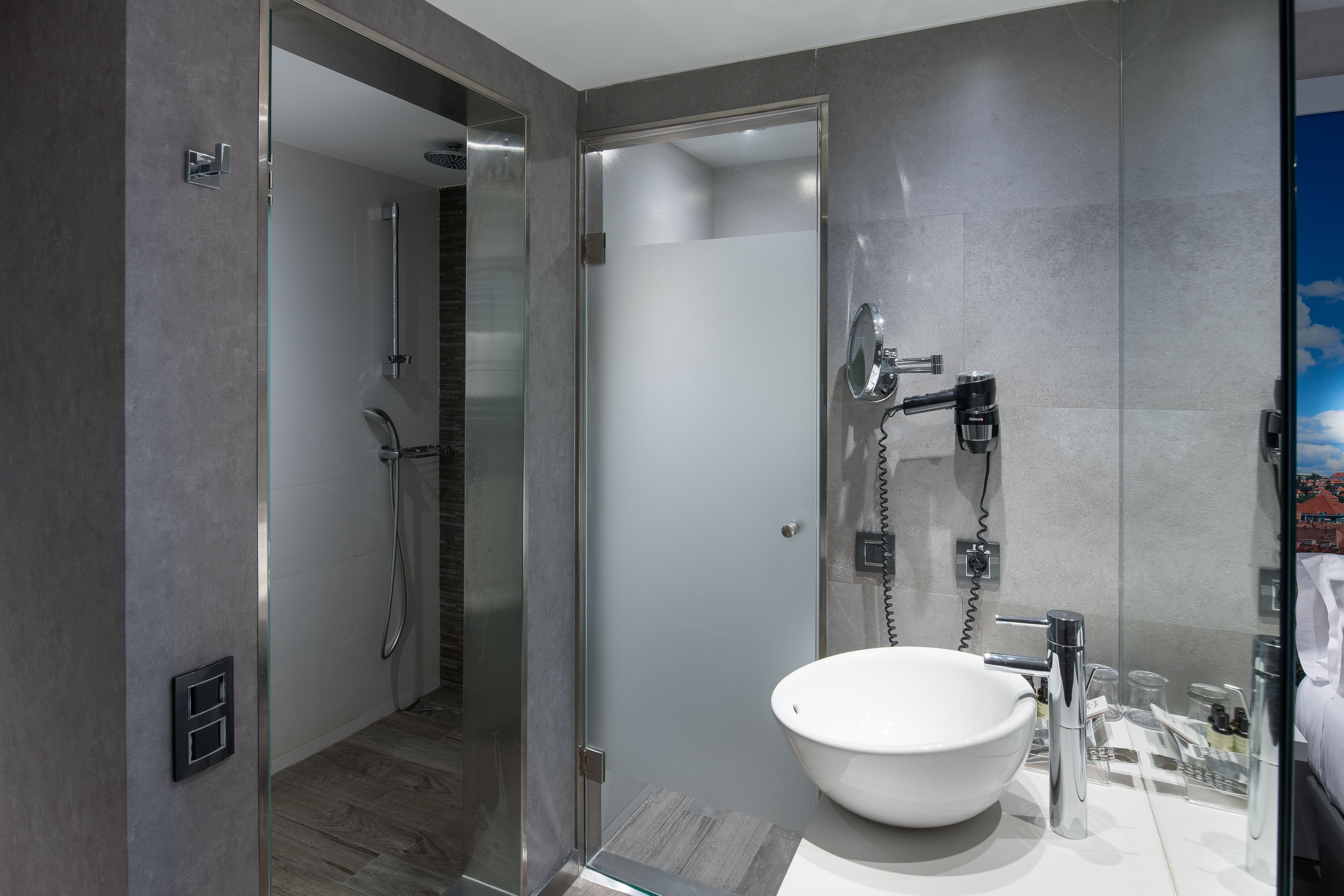 Une salle de bain moderne avec une douche à parois de verre, un lavabo blanc et un miroir.