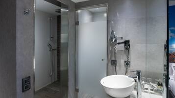 Une salle de bain moderne avec une douche à parois de verre, un lavabo blanc et un miroir.