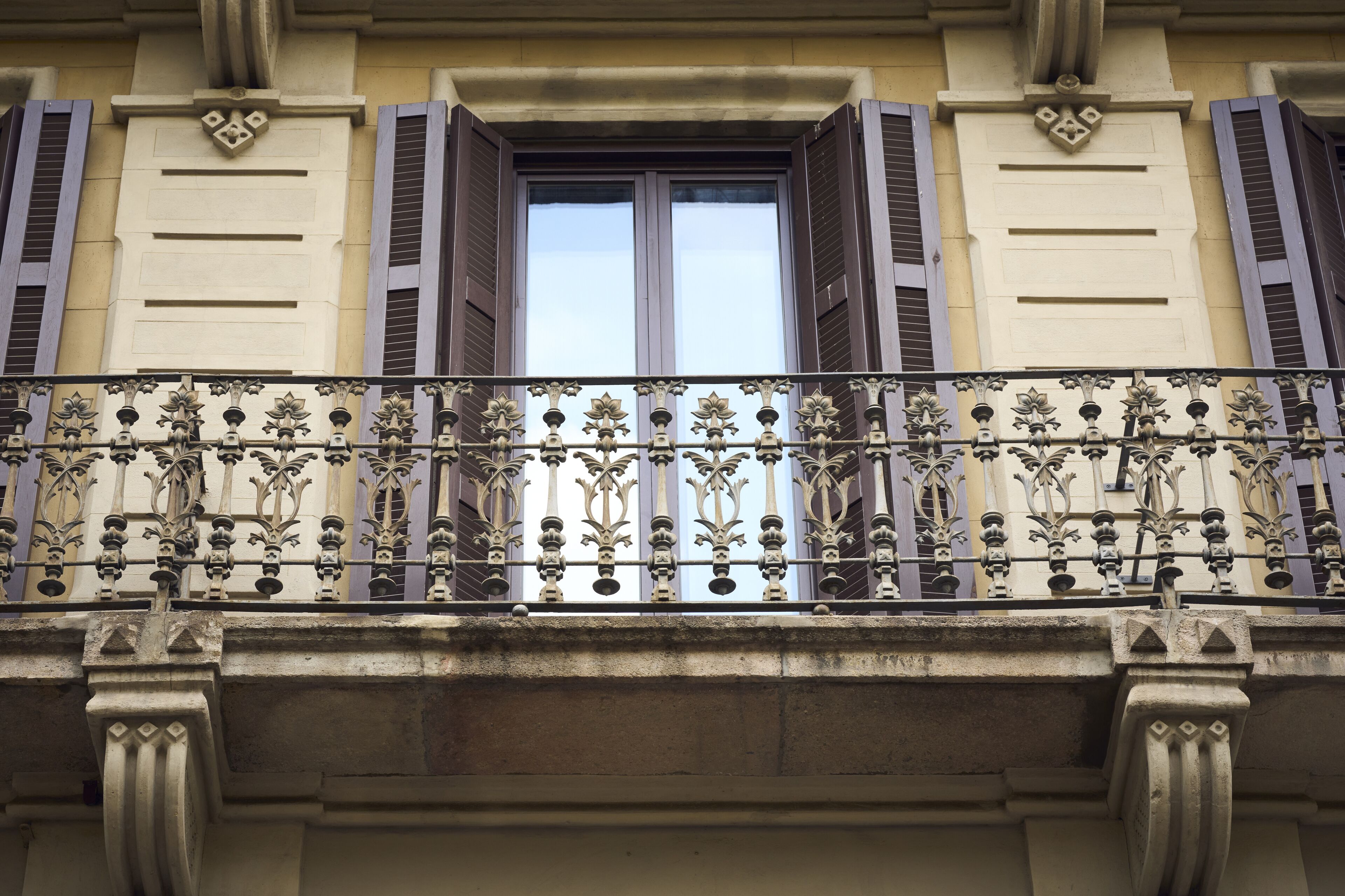 Varanda com grades de metal decorativas e persianas.