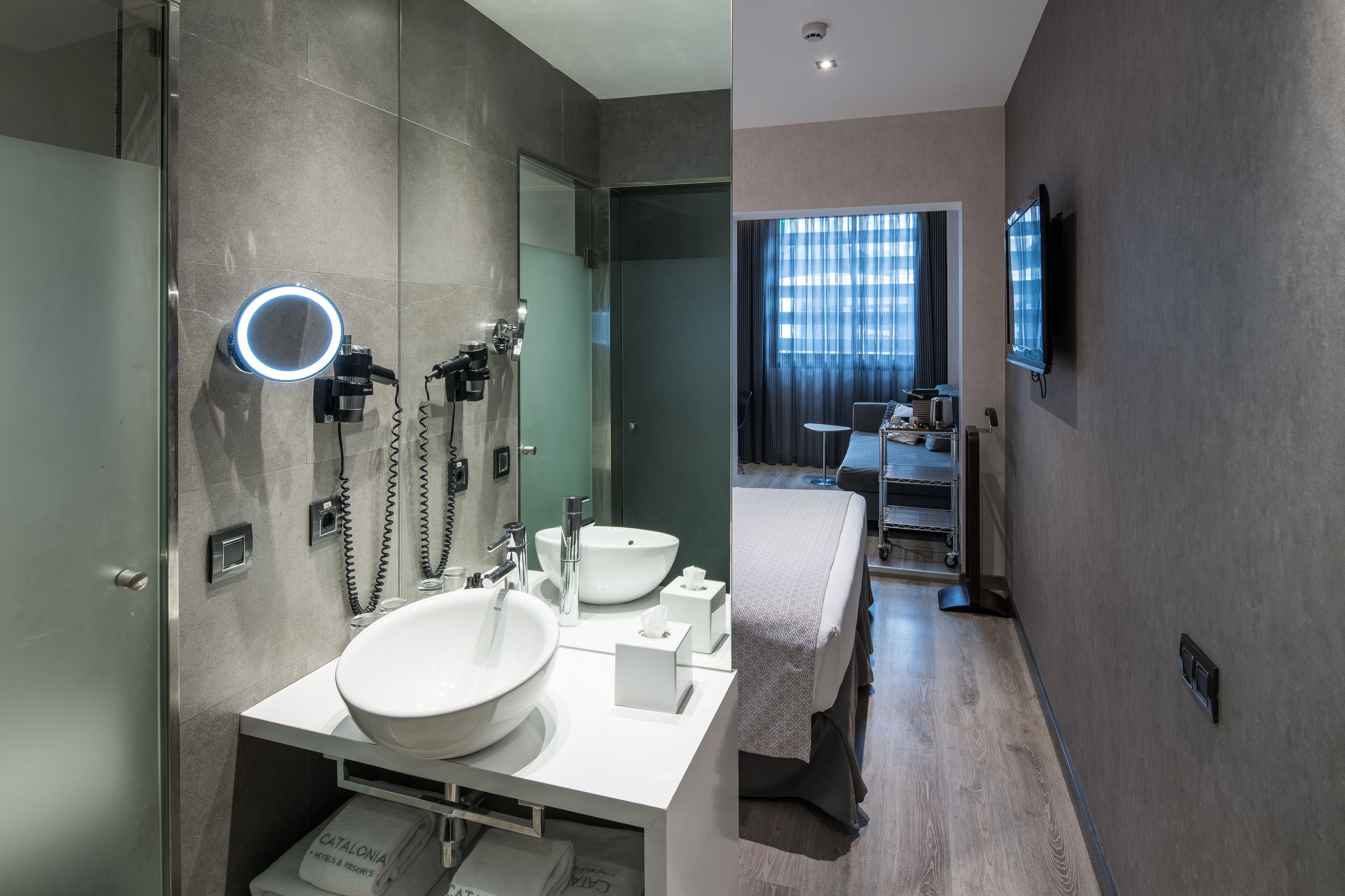Un baño moderno con un lavamanos grande, un espejo y una luz de aro.