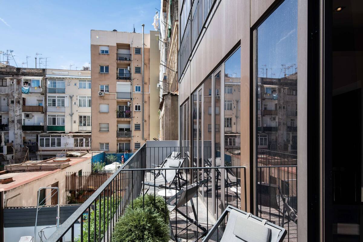 Ein modernes Gebäude mit großen Fenstern und einem Balkon mit Stühlen.