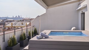 A rooftop terrace with a swimming pool, potted plants, and a view of the city skyline. - Catalonia Gran Vía BCN (Barcelona)