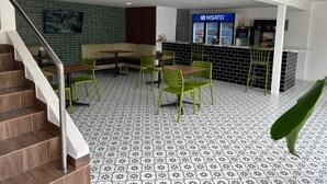 A modern interior with a staircase, a seating area with a bench and tables, and a counter with a sign reading "NISATO". - Express Inn Panama International Airport Hostel (Tocumen)