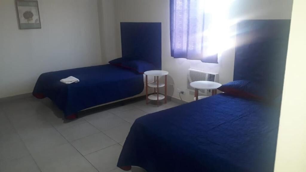 A room with two beds, a small round table, and a window with curtains.