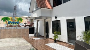 A modern building with a tiled patio, a mural with palm trees and the word "Panama," and a large window. - Express Inn Panama International Airport Hostel (Tocumen)