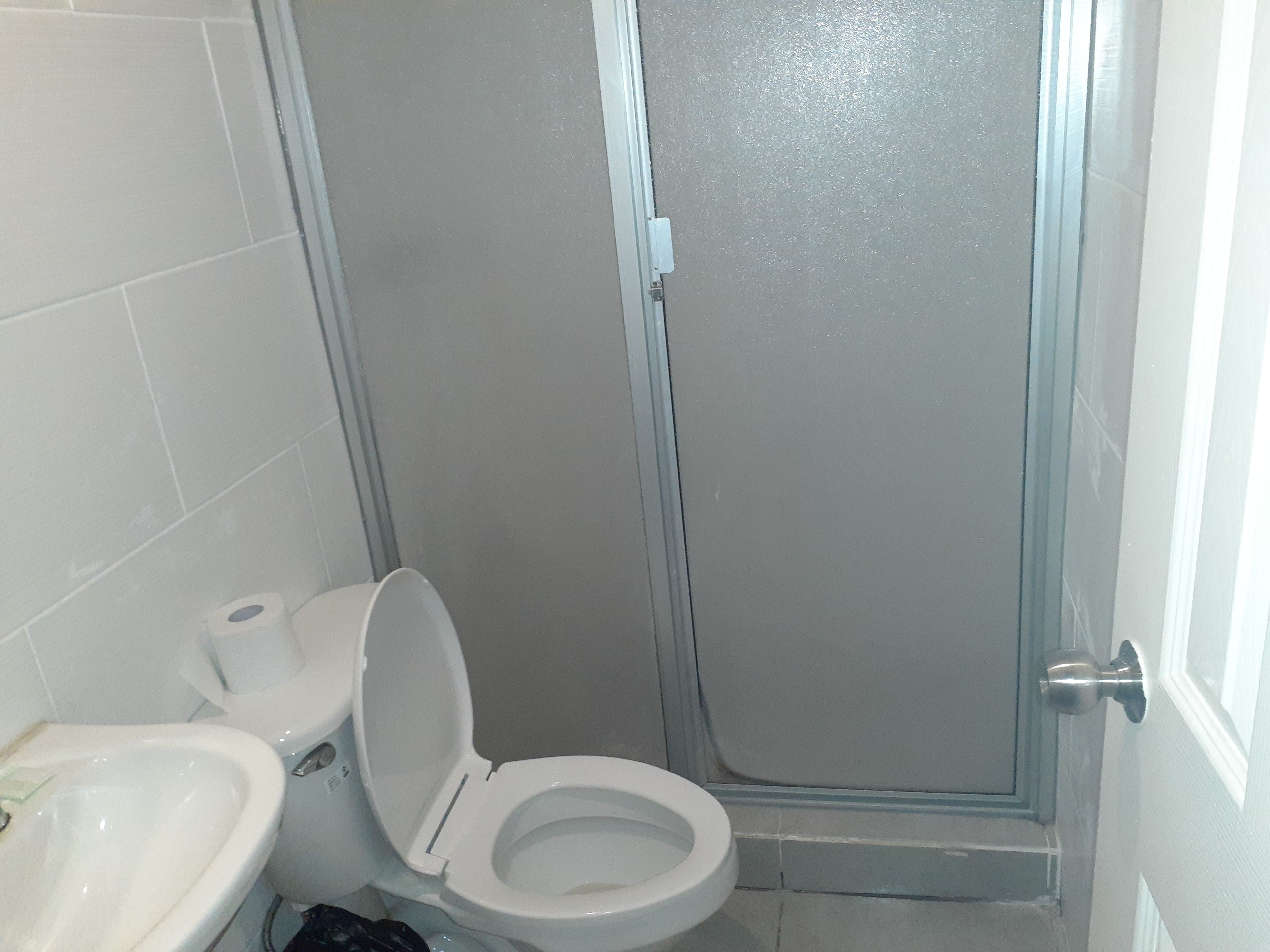 A bathroom with a toilet, sink, and shower stall.