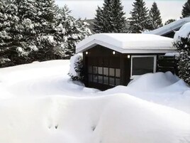 A snow-covered house with a garage and a small porch area.