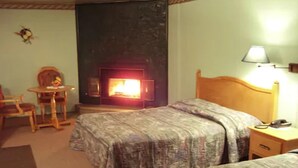 A hotel room with two beds, a small table with chairs, a lamp, and a fireplace. - Auberge Mountain View Inn (Mont-Tremblant)