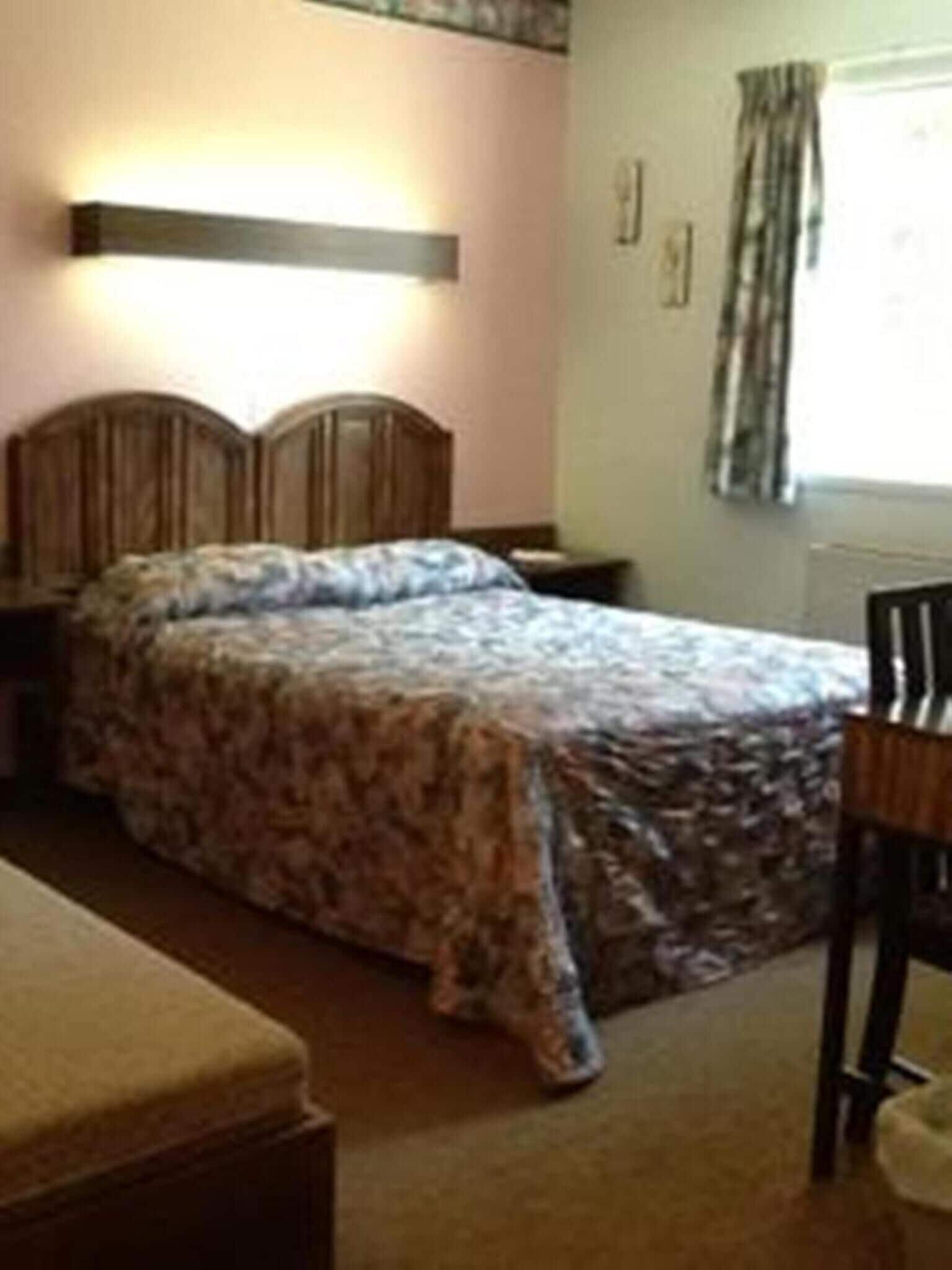 A bedroom with a bed, bedside table, and a chair.