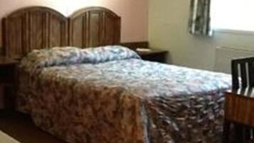 A bedroom with a bed, bedside table, and a chair.