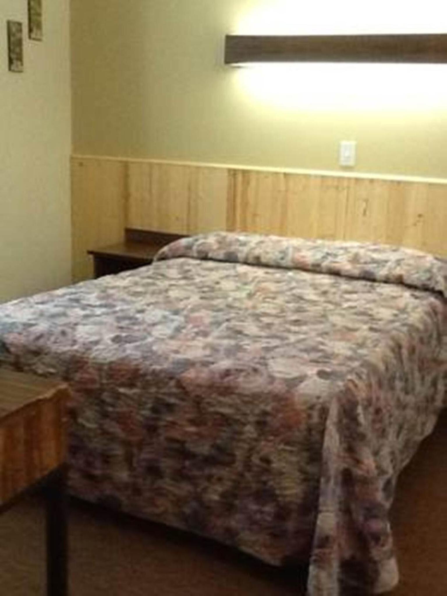 A bedroom with a bed, wooden headboard, and a nightstand.