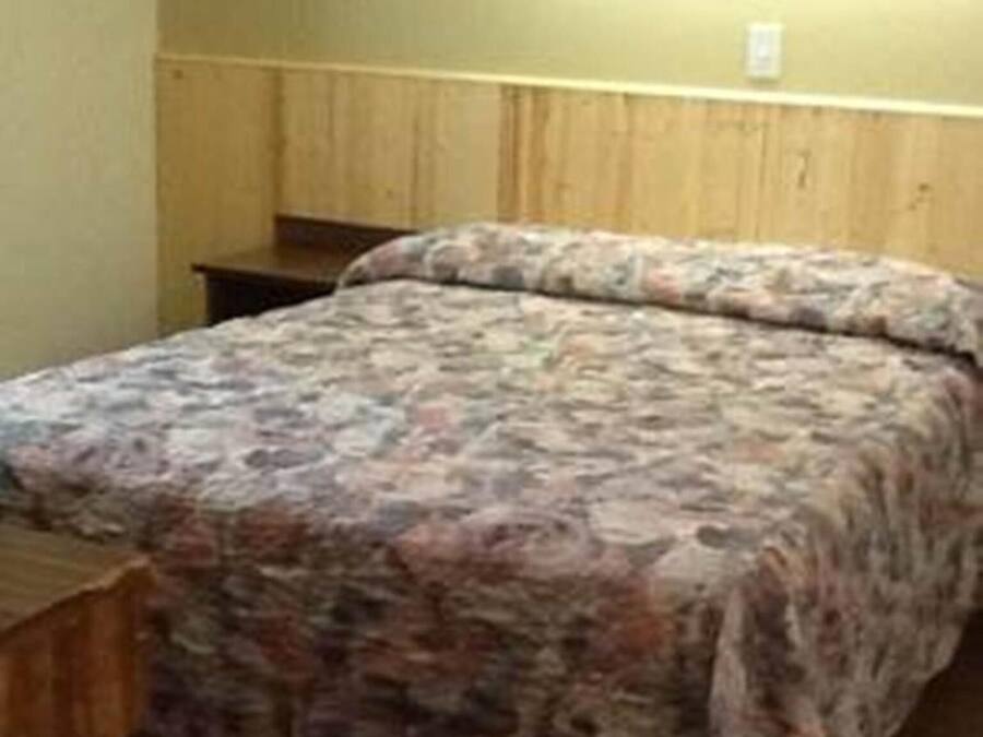 A bedroom with a bed, wooden headboard, and a nightstand.