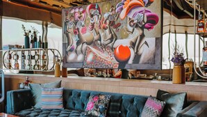 A modern lounge area with a large sofa, a coffee table, and a mural on the wall. - The Smallville Hotel (Beirut)