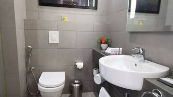 Un baño moderno con inodoro, bidé, lavabo y un cuadro enmarcado en la pared.