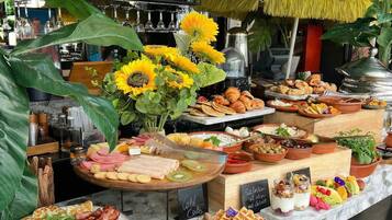 Un bufé con diversos alimentos, entre ellos bollería, frutas y salsas.