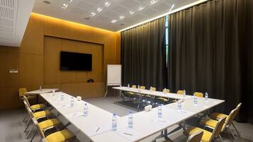 A conference room with a long table, yellow chairs, a whiteboard, and a projector.