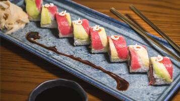 A sushi dish with a blue plate and chopsticks on a wooden table.