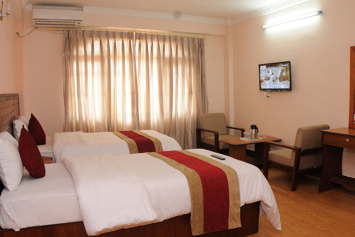 A hotel room with two beds, a desk, a chair, a TV, and a window with curtains.